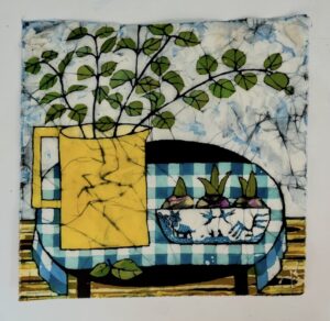 Artwork of vase with leaves on checkered tablecloth.
